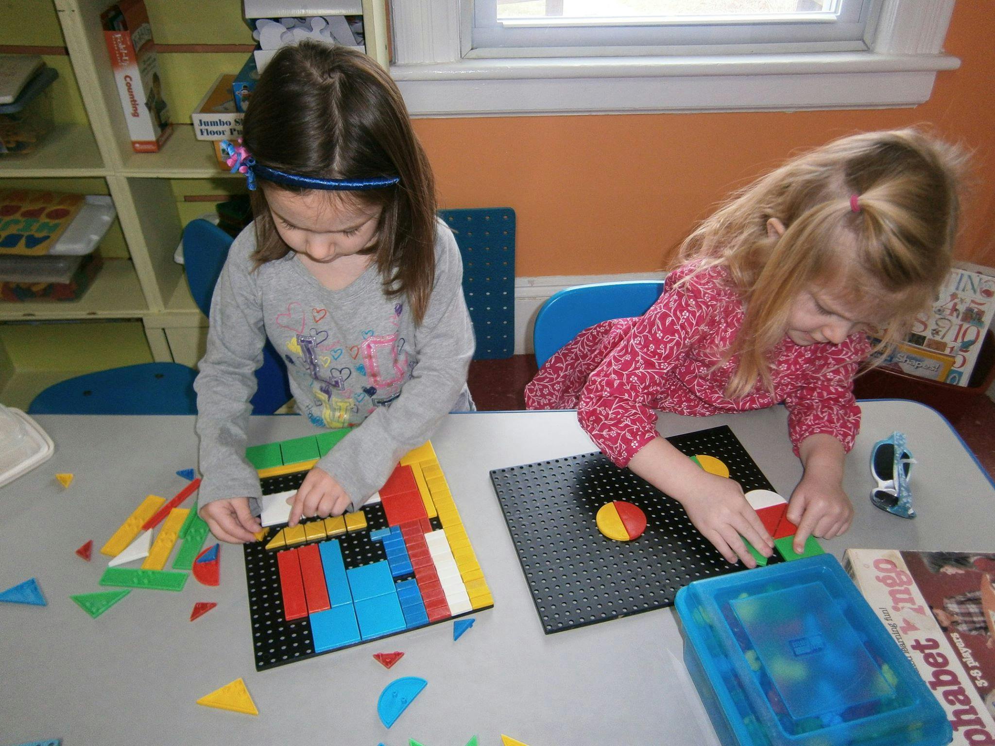 Two children playing with colorful building blocks at a table