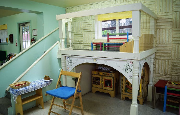 Play structure with a window and furniture underneath, next to a staircase
