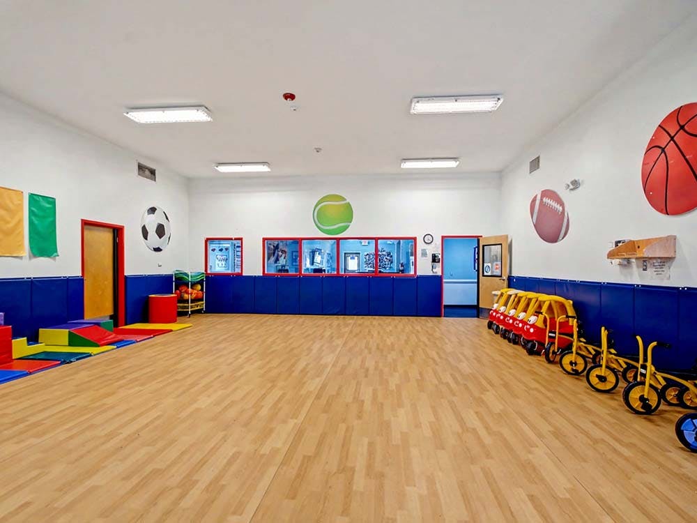 Indoor playroom with sports-themed wall decor and child-sized bikes