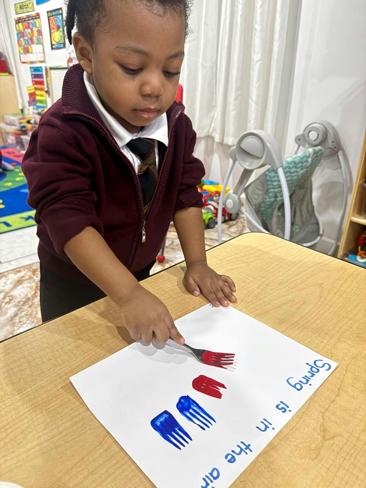 Child using a fork to make painted prints on paper