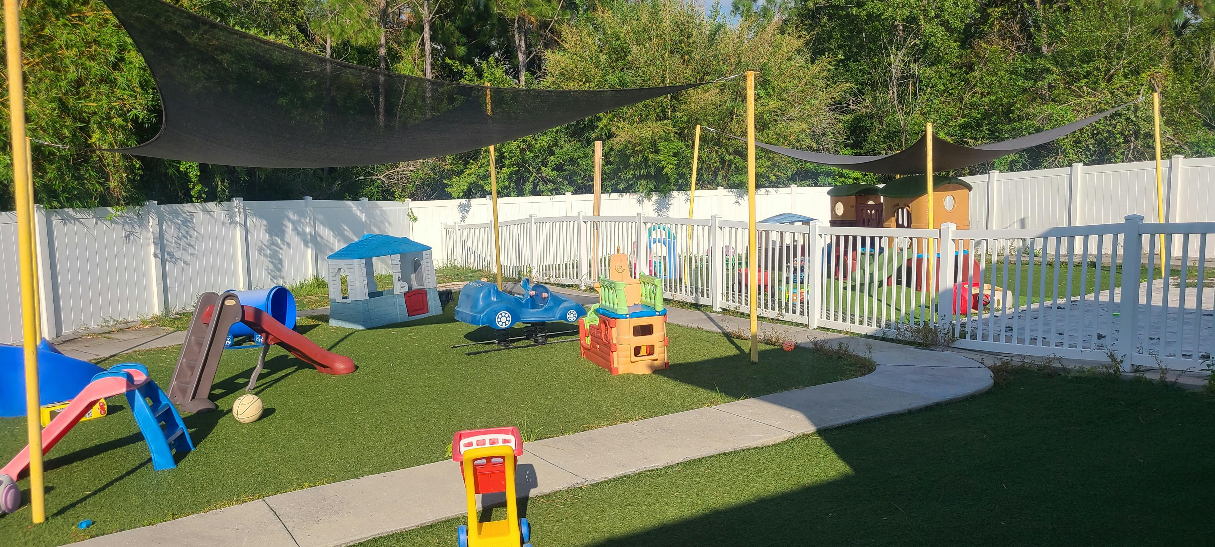 Outdoor playground with artificial turf, slides, and play structures under shade sails