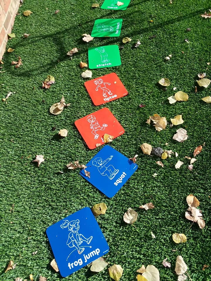 Colorful activity squares on green turf with words like "frog jump" and "squat"