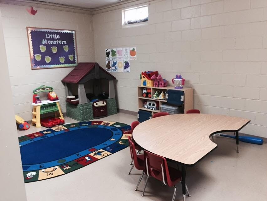 Playroom with a playhouse, rug, and crescent-shaped table