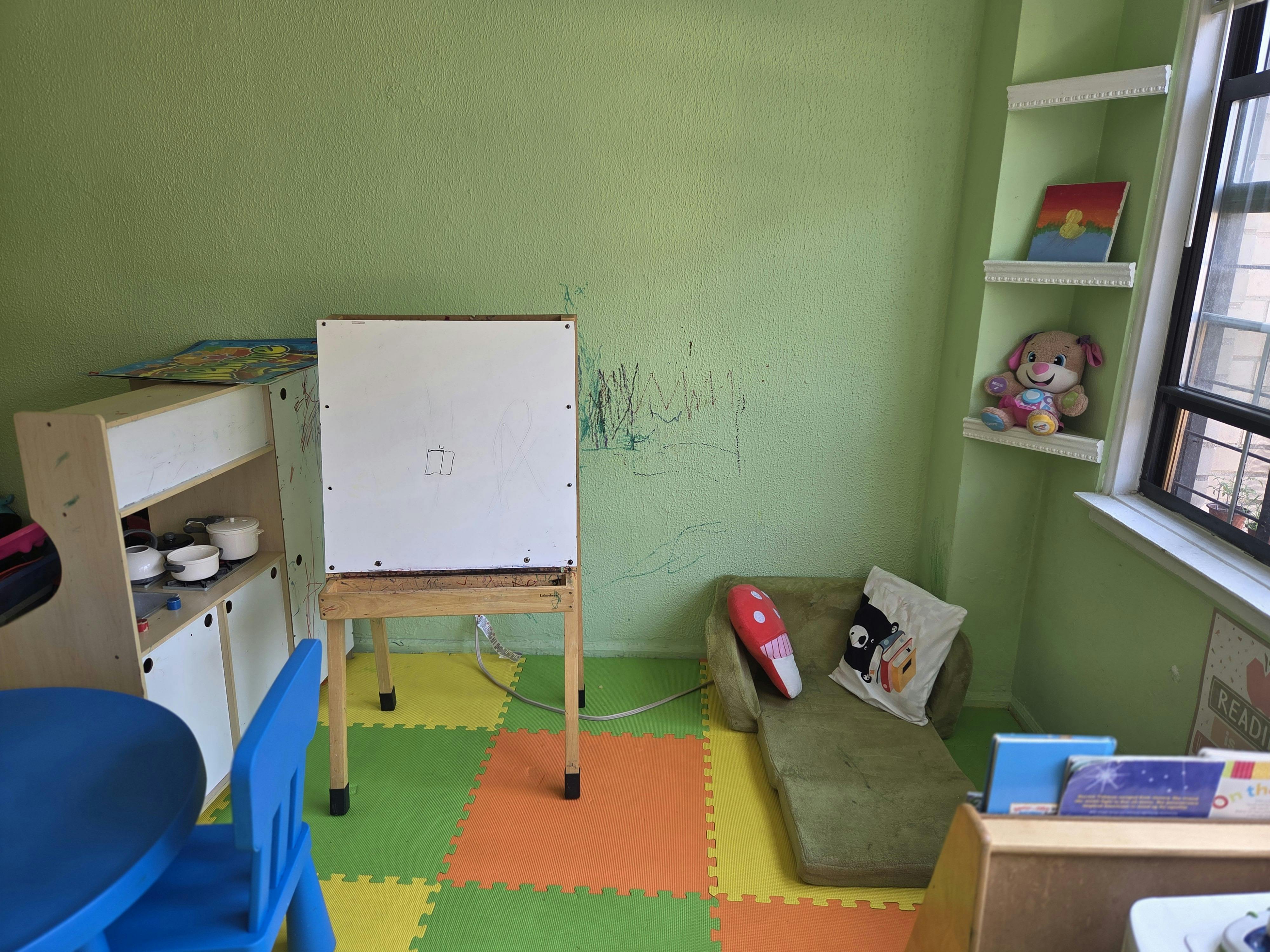 Easel and furniture in a room with green walls and colorful floor tiles