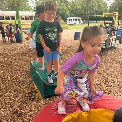 Children playing on playground equipment on a woodchip surface