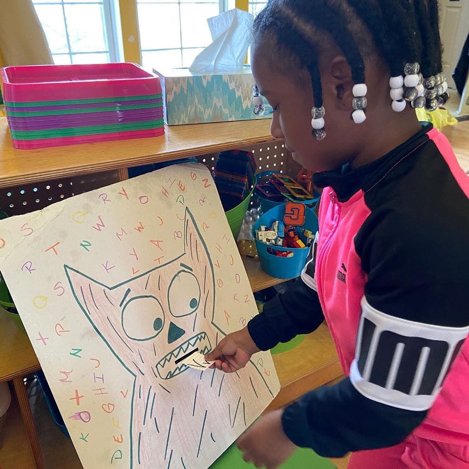 Child inserting a small card into a drawing of a monster