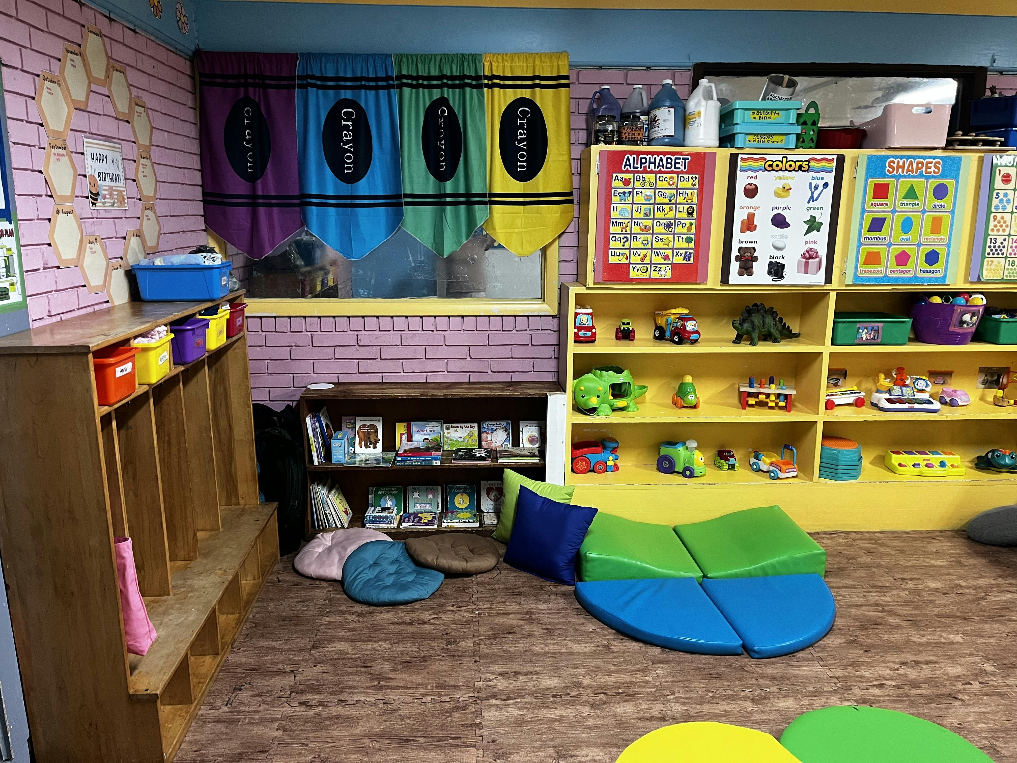 Classroom with cubbies, shelves of toys, and colorful floor cushions