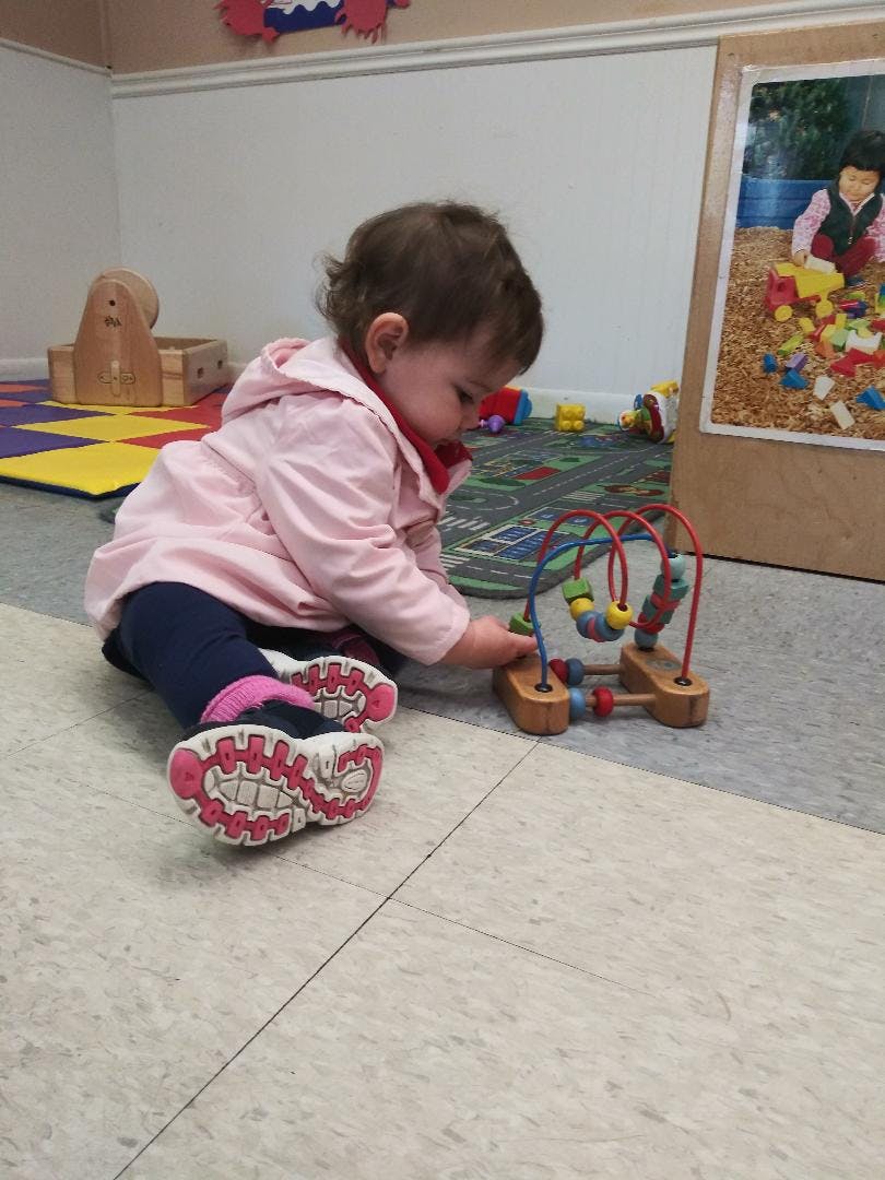 Child playing with a bead maze toy on the floor