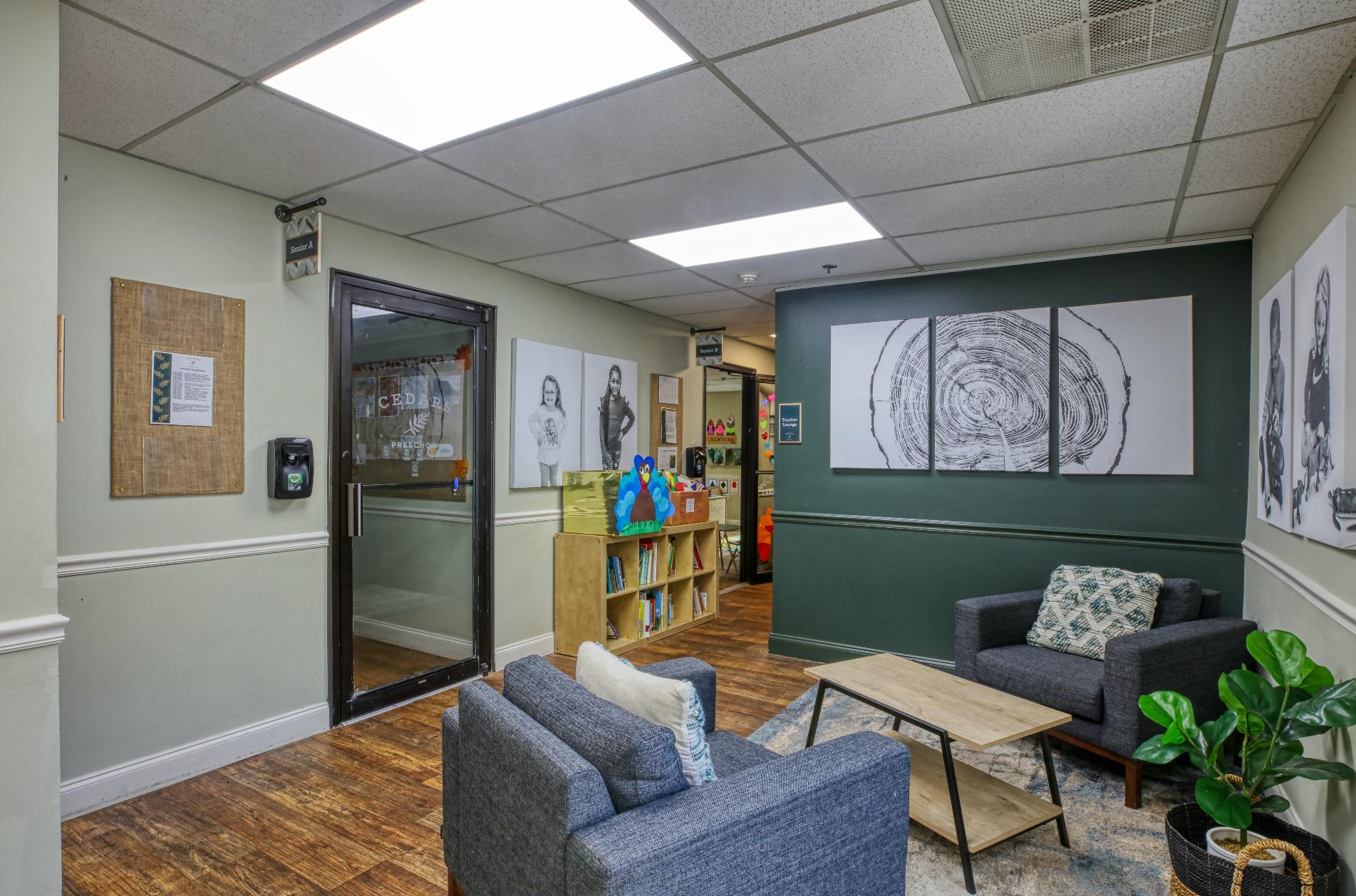 Lobby area with two armchairs and a small table, a glass door, and artwork on the walls