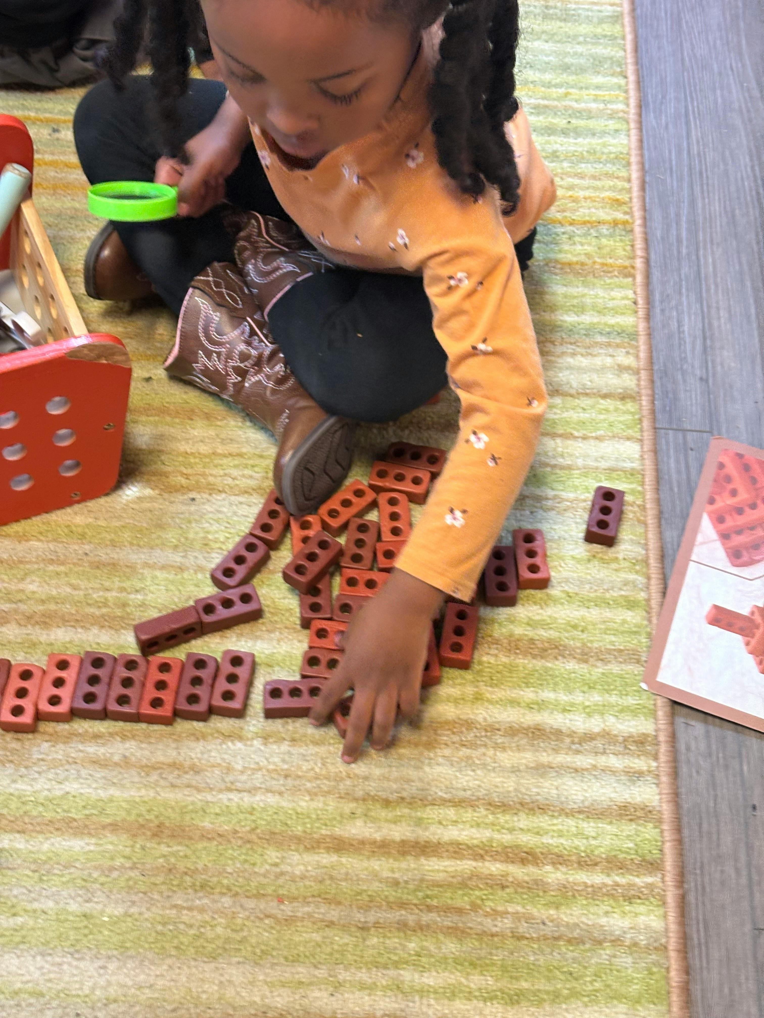 Child playing with toy bricks on a striped rug