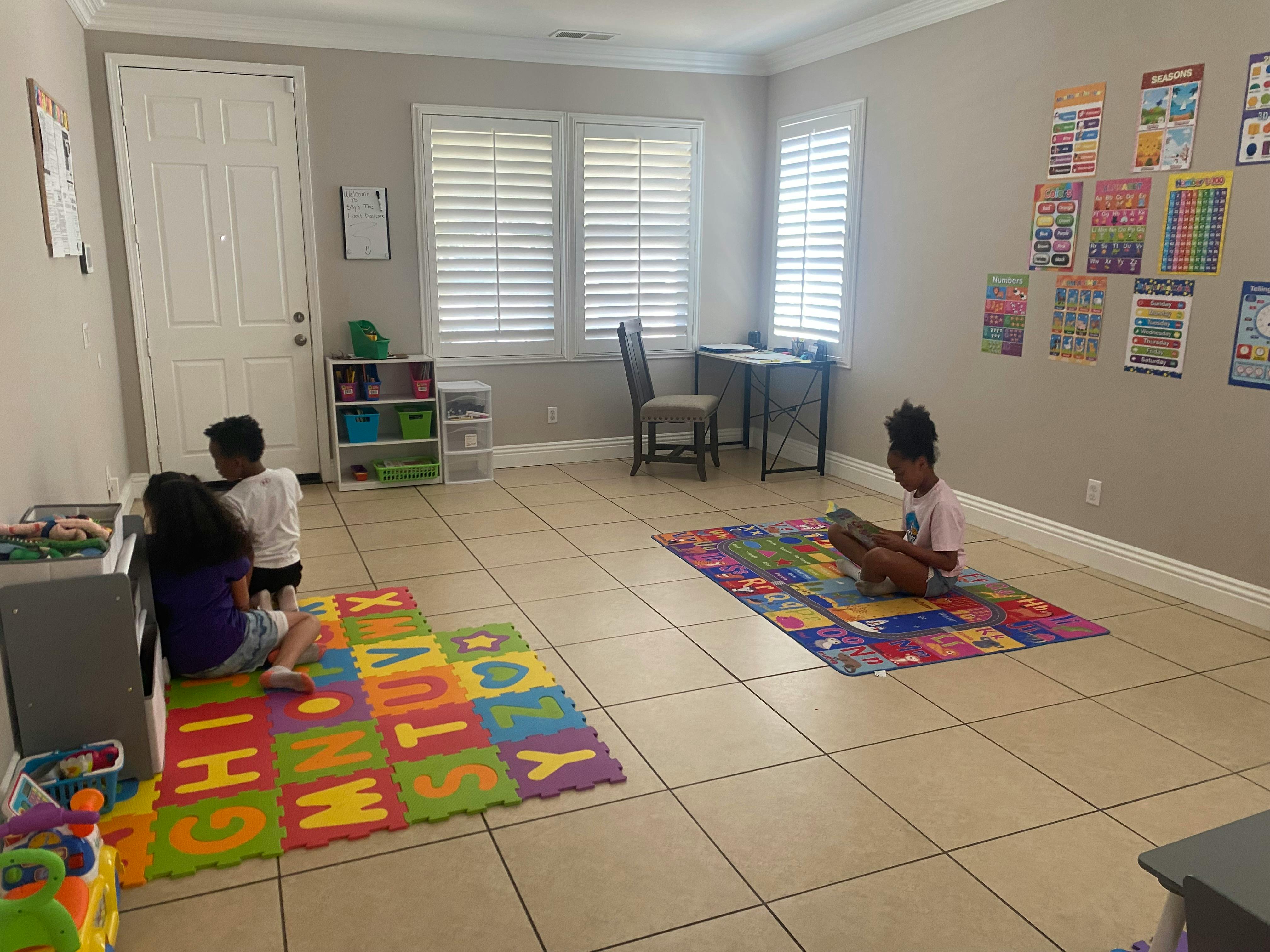 Three children playing on alphabet mats in a room