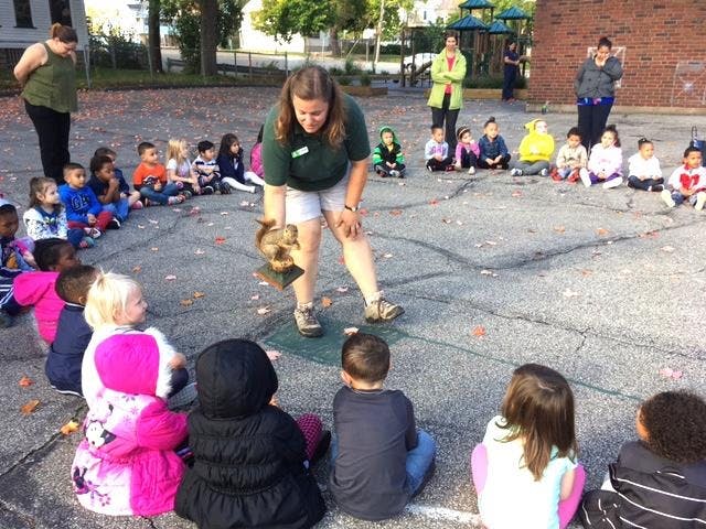 Adult showing an object to children sitting in a circle outdoors