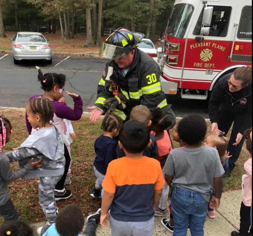 Firefighter in uniform interacting with a group of children outdoors