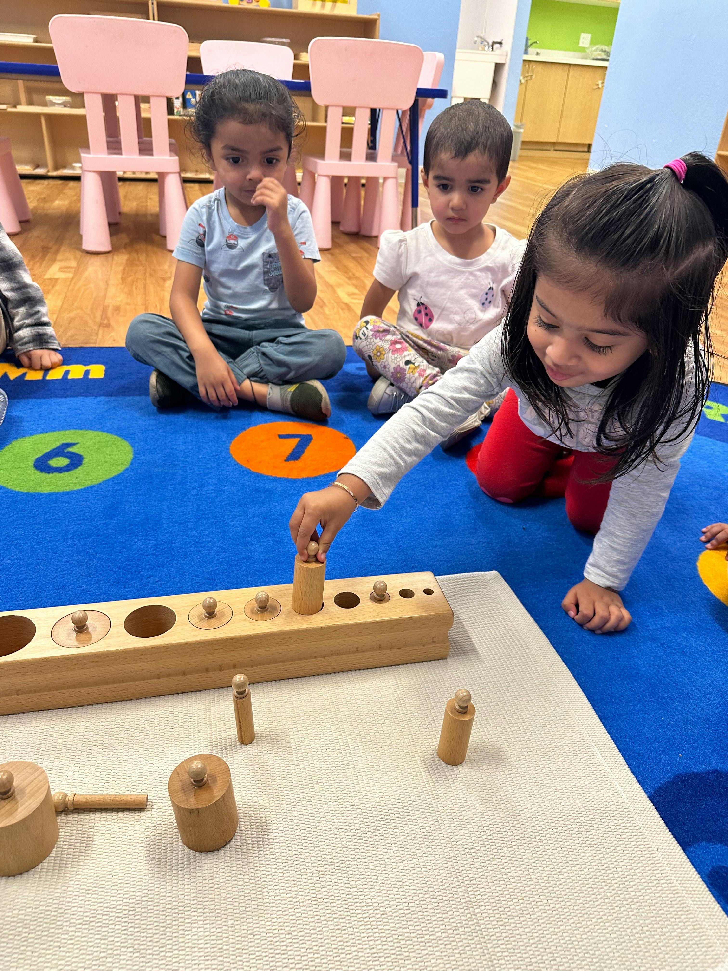 Child playing with wooden cylinder blocks on a blue mat