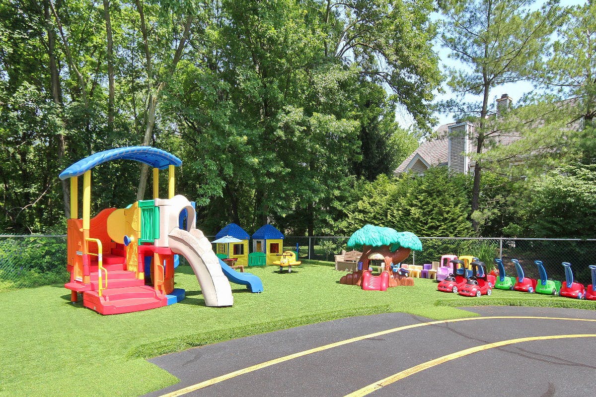 Outdoor playground with colorful slides, swings, and ride-on toys on green turf