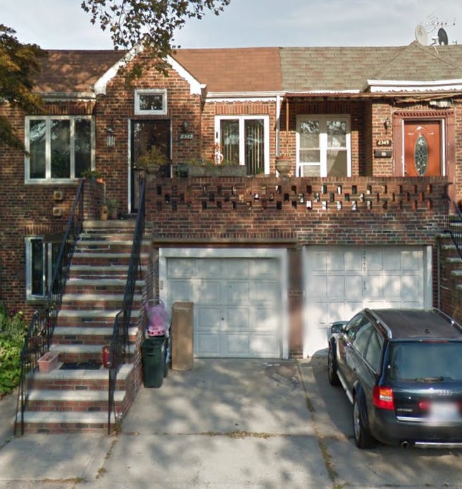 Brick residential building with two garages and a parked car