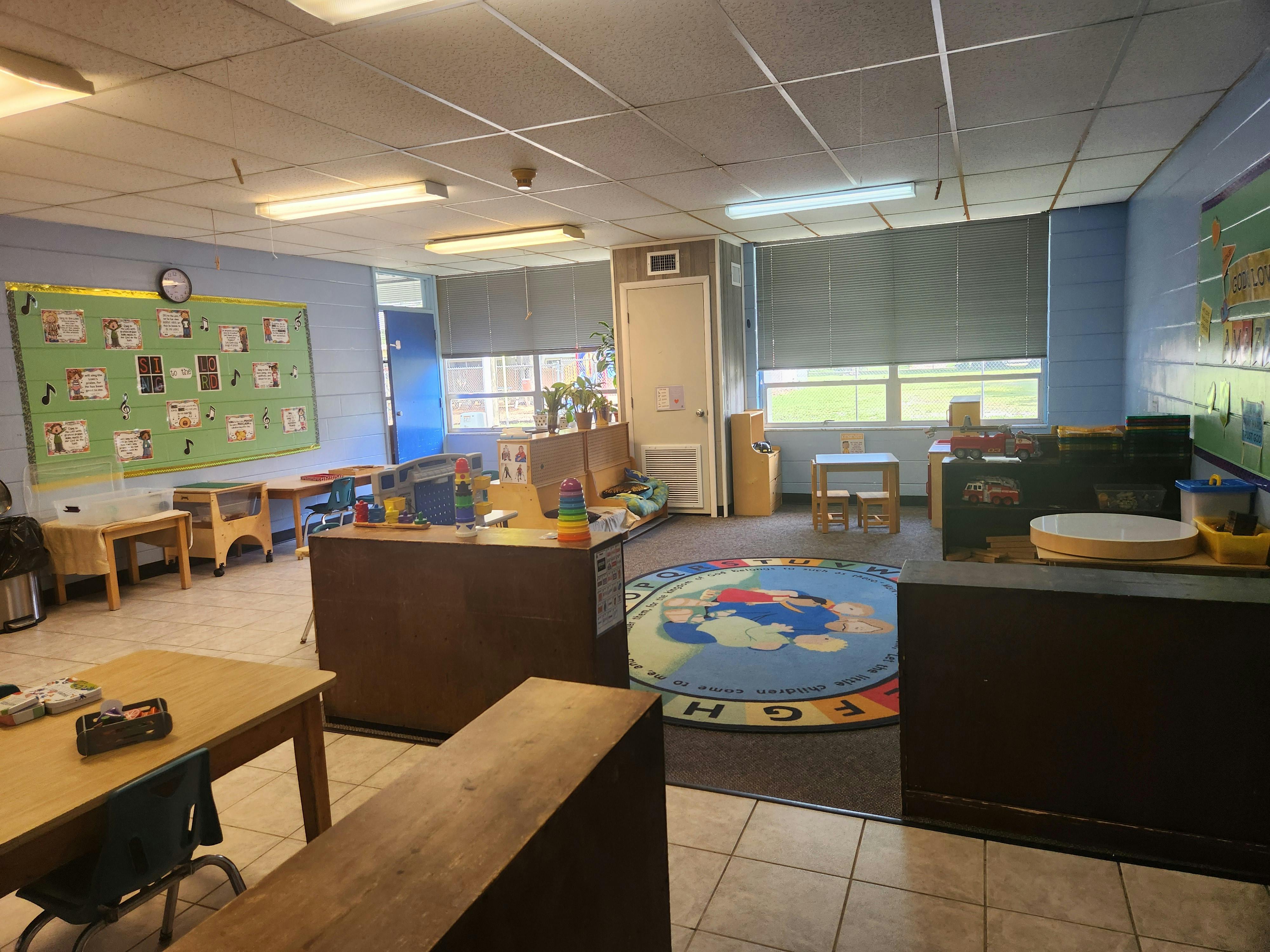 Empty classroom with small tables, chairs, and a world map rug