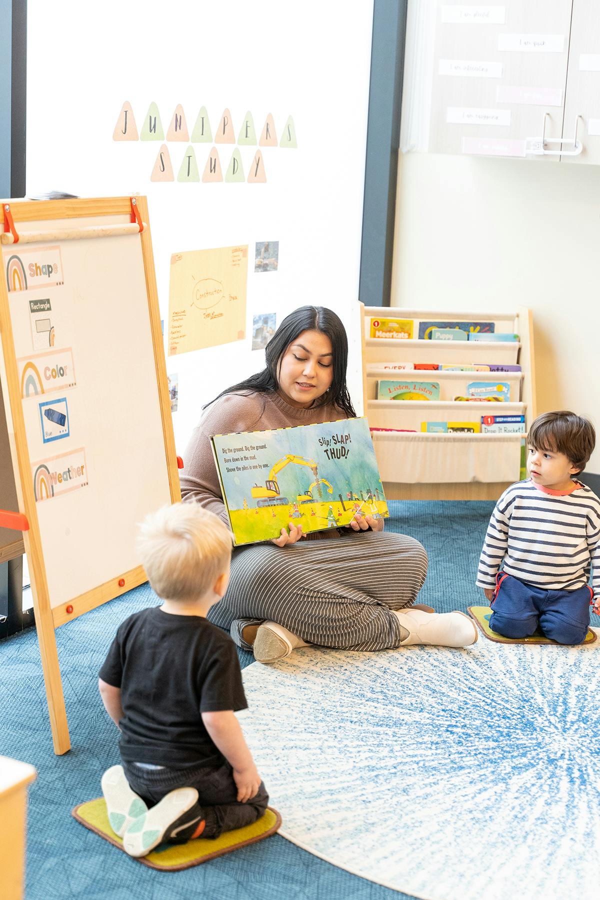Person reading a book to two children in a classroom
