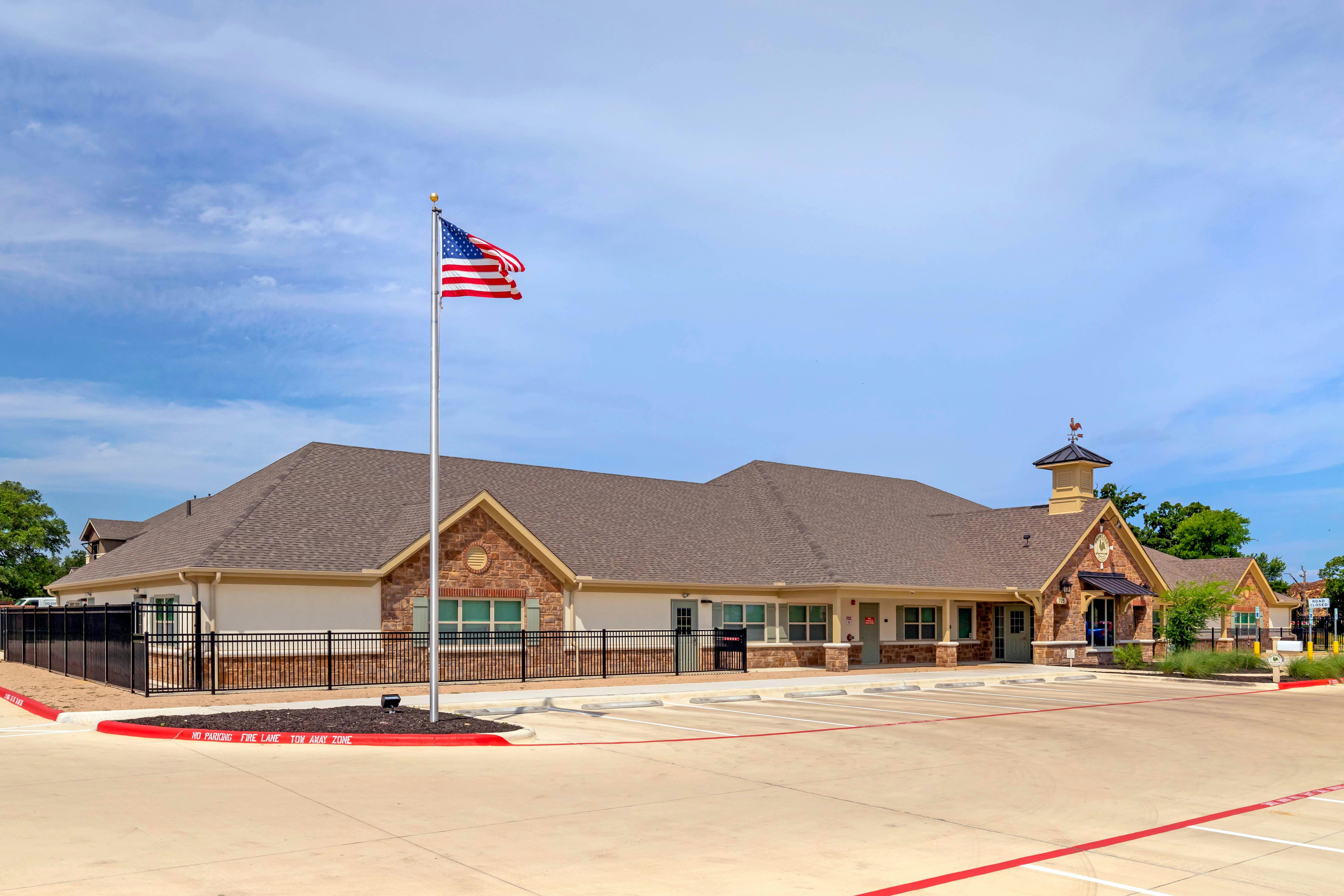 A low-angle shot of a building with stone and stucco siding, an American flag