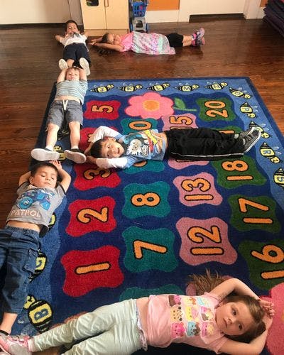 Children lying on a colorful rug with numbers