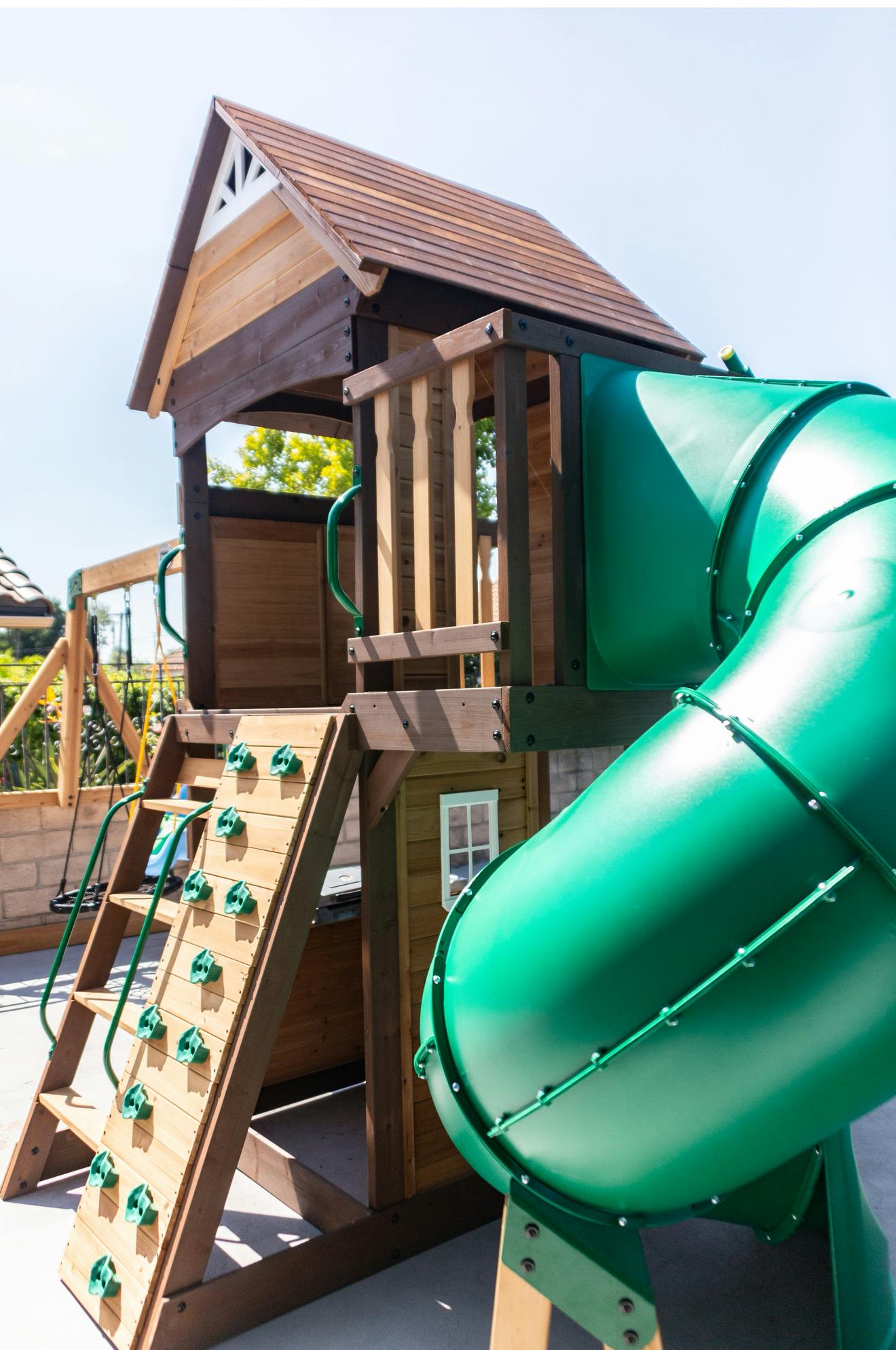 Wooden playground with a green slide and climbing wall