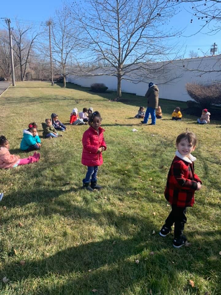 Children and an adult outdoors on a grassy area