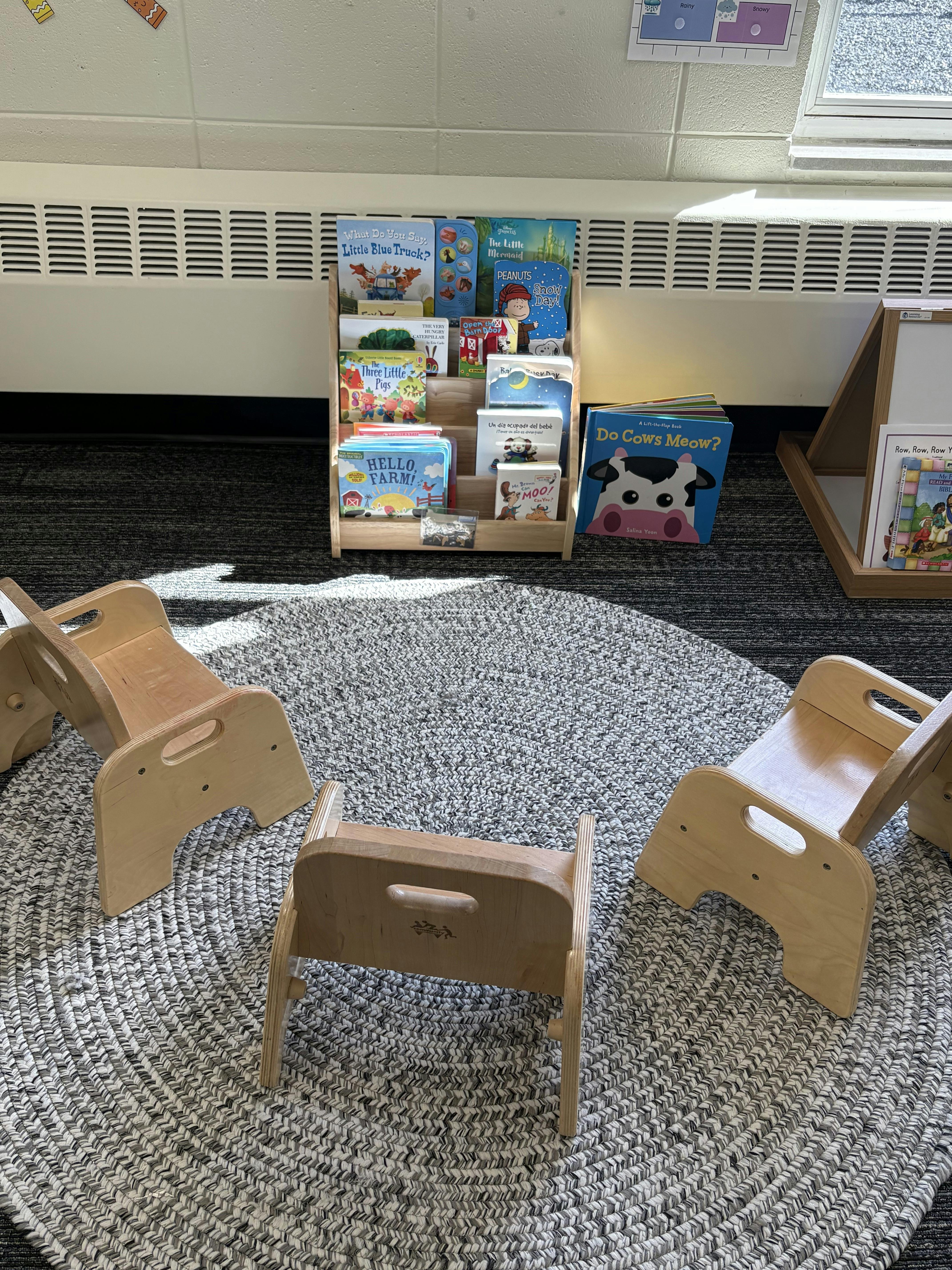 Small chairs on a circular rug in front of a book display with children's books