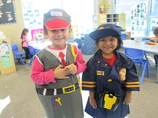 Two children in costumes, one in a construction worker costume, one in a police costume