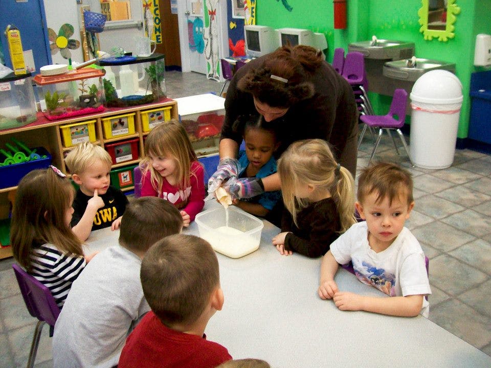 Adult and children gathered around a table pouring liquid into a container