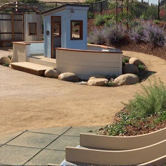Small playhouse and boat-shaped structure in a dirt area