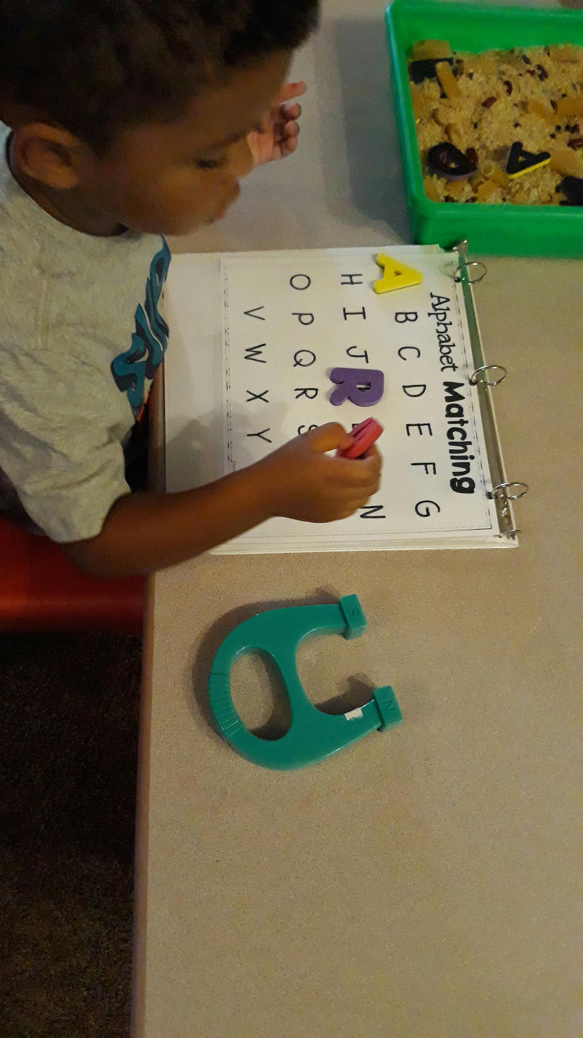 Child matching letters on an "Alphabet Matching" activity sheet