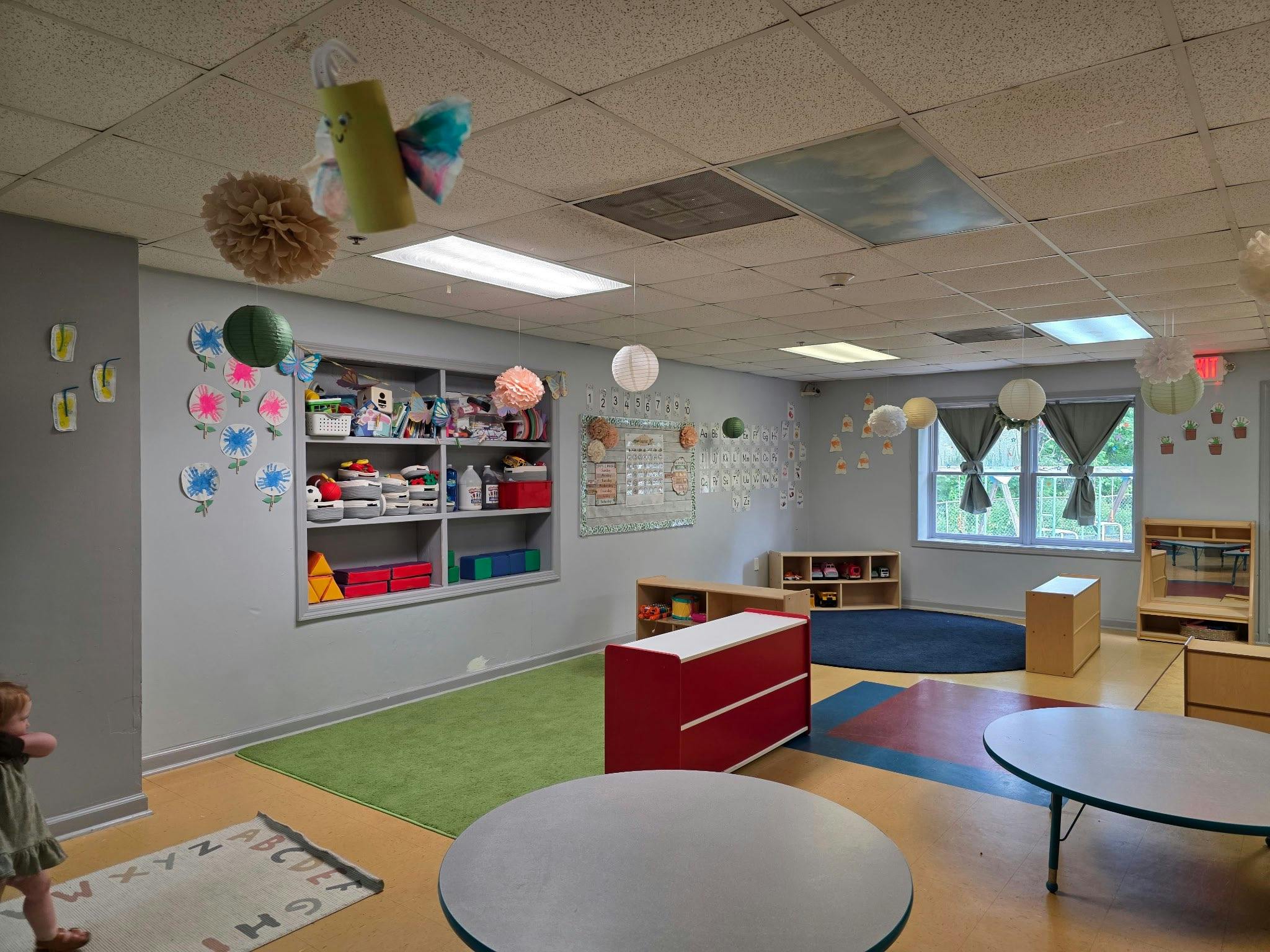 Classroom decorated with paper lanterns and crafts, with a child in the foreground
