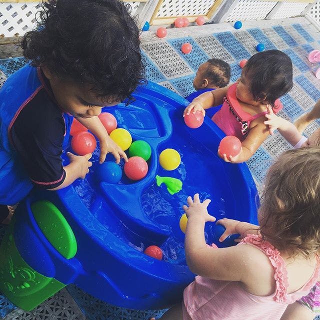 Children playing with colorful balls in a blue water table