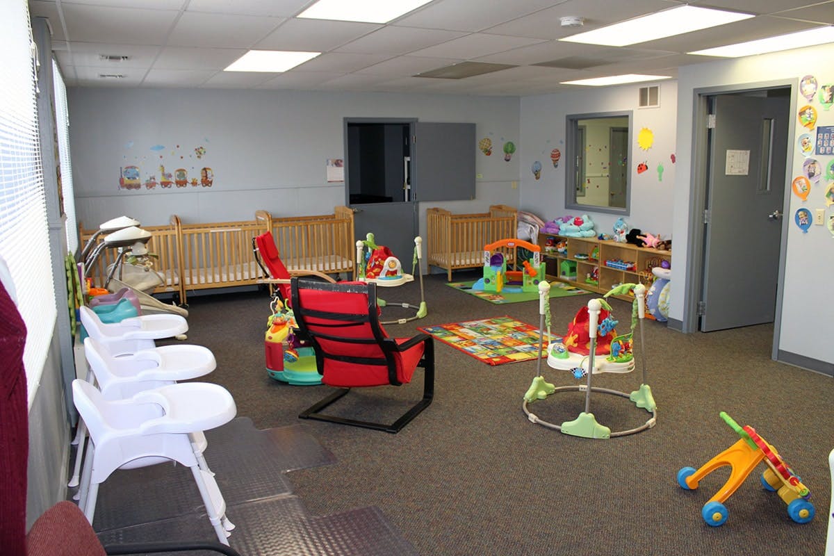 Nursery room with cribs, high chairs, and baby play equipment