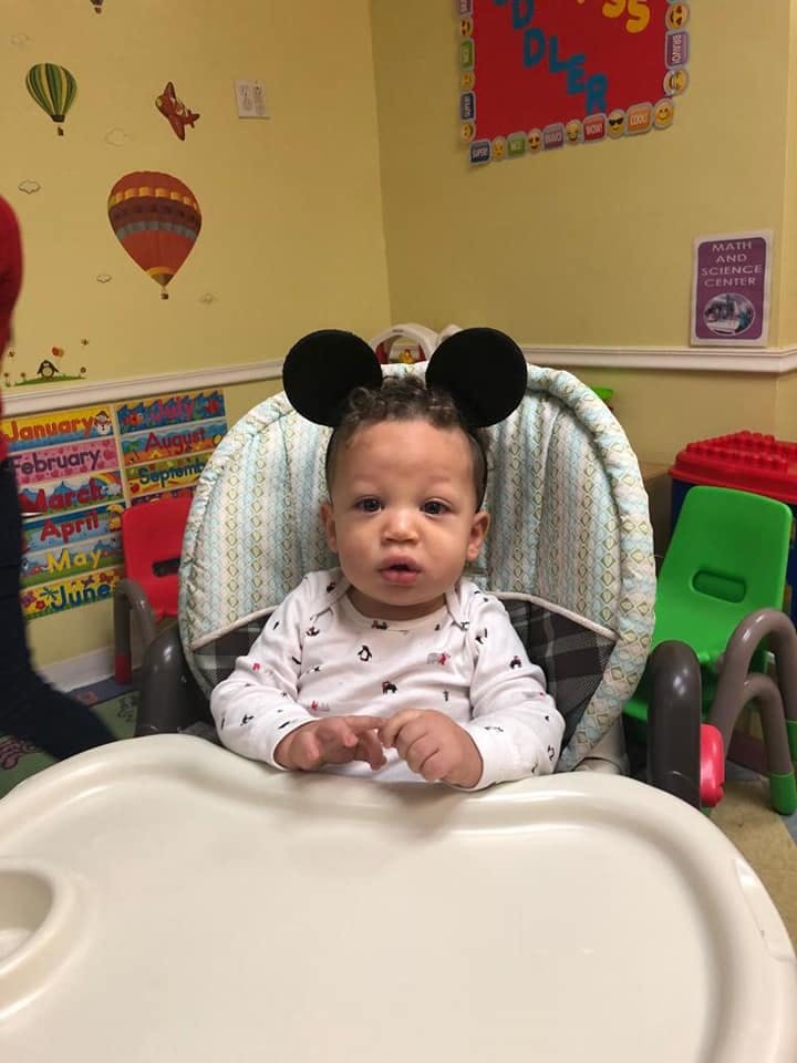 Child in a high chair wearing Mickey Mouse ears