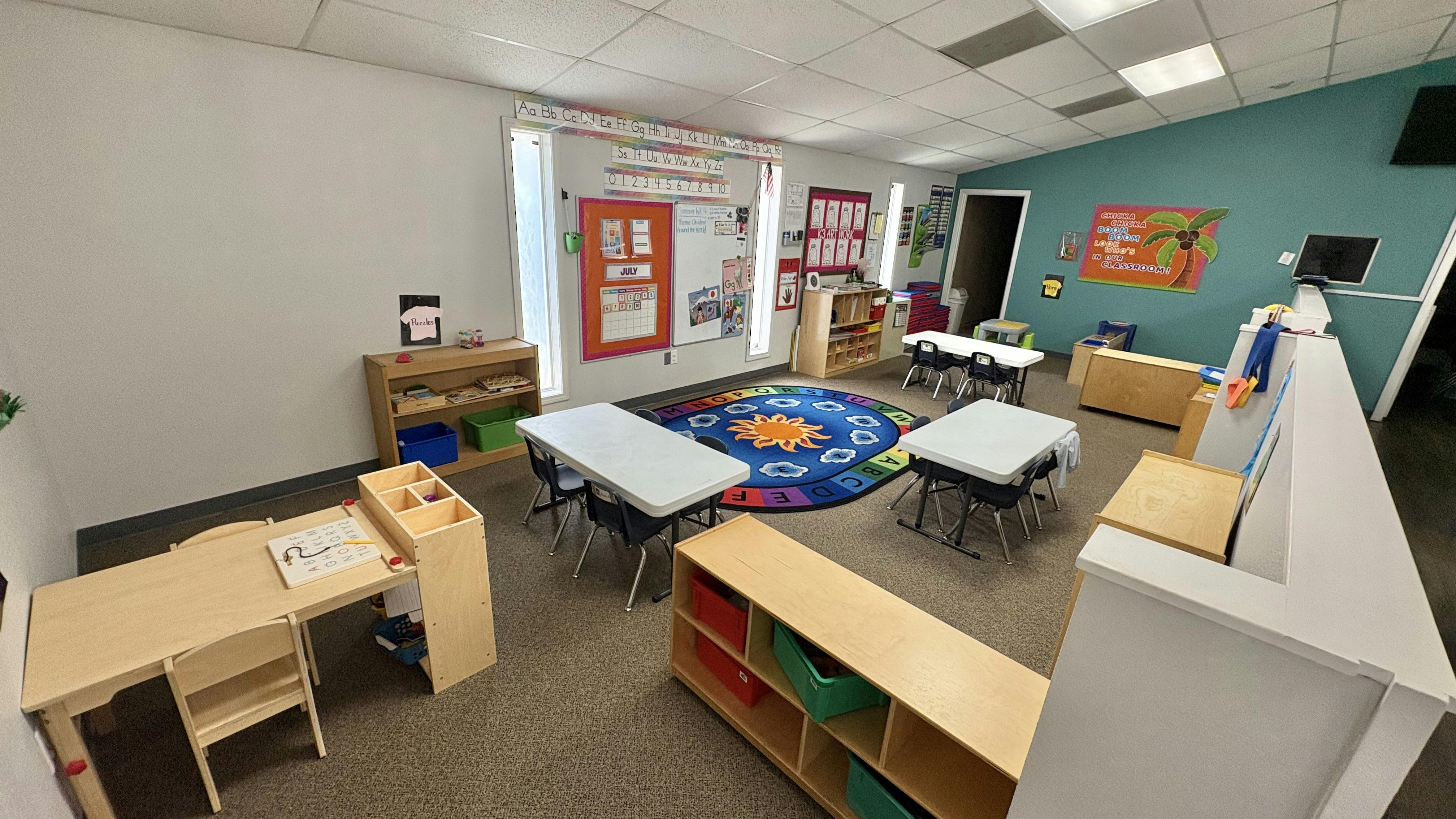 Classroom with small tables and chairs, a colorful rug, and storage shelves