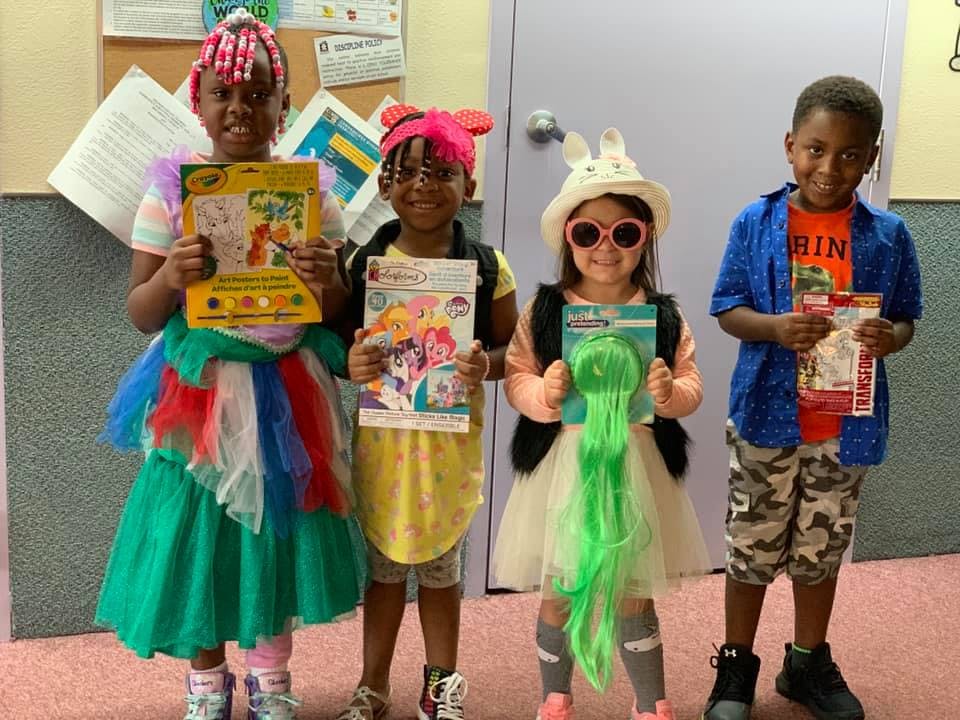 Four children in costumes holding books