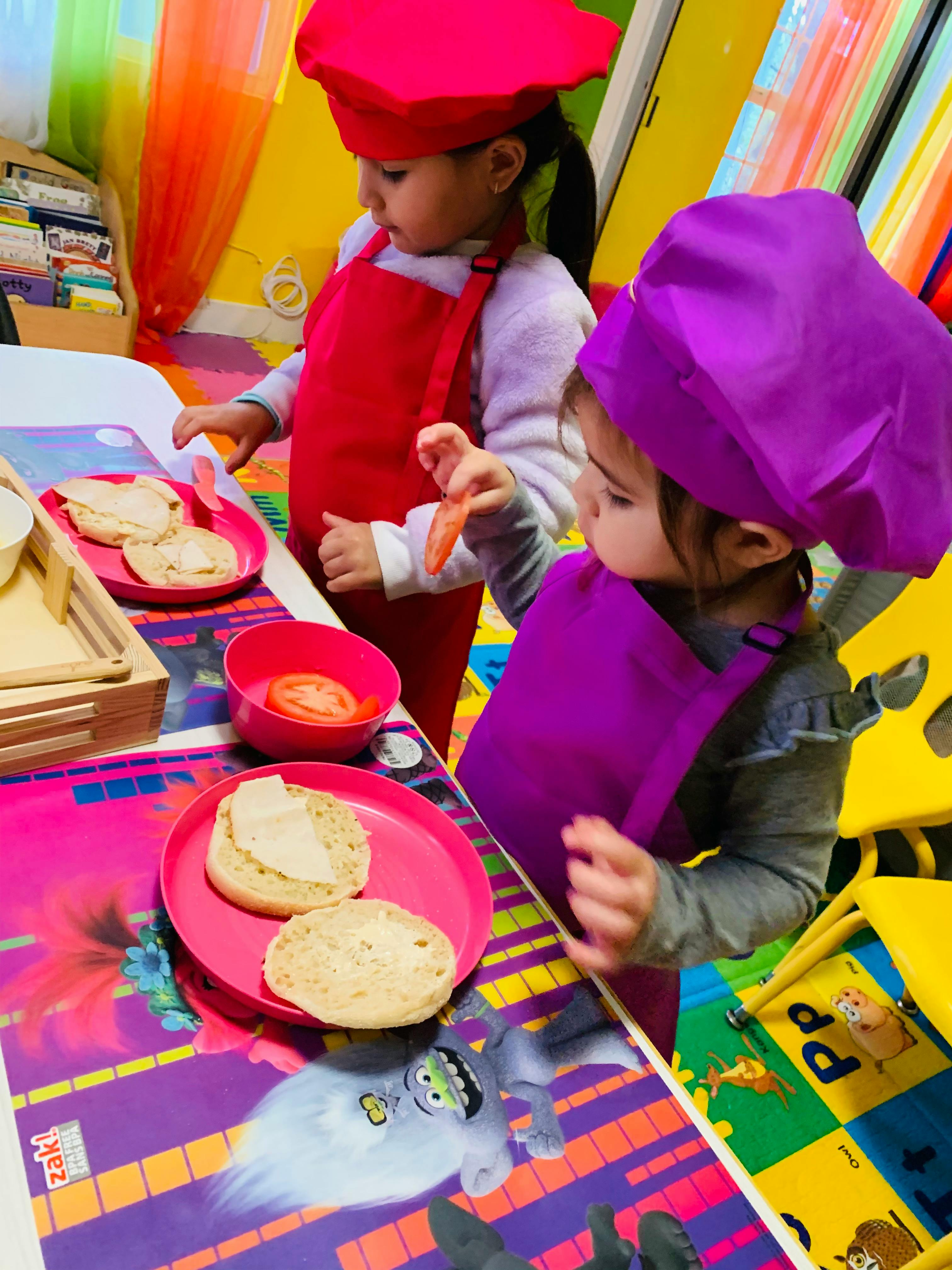 Two children in chef hats and aprons preparing food