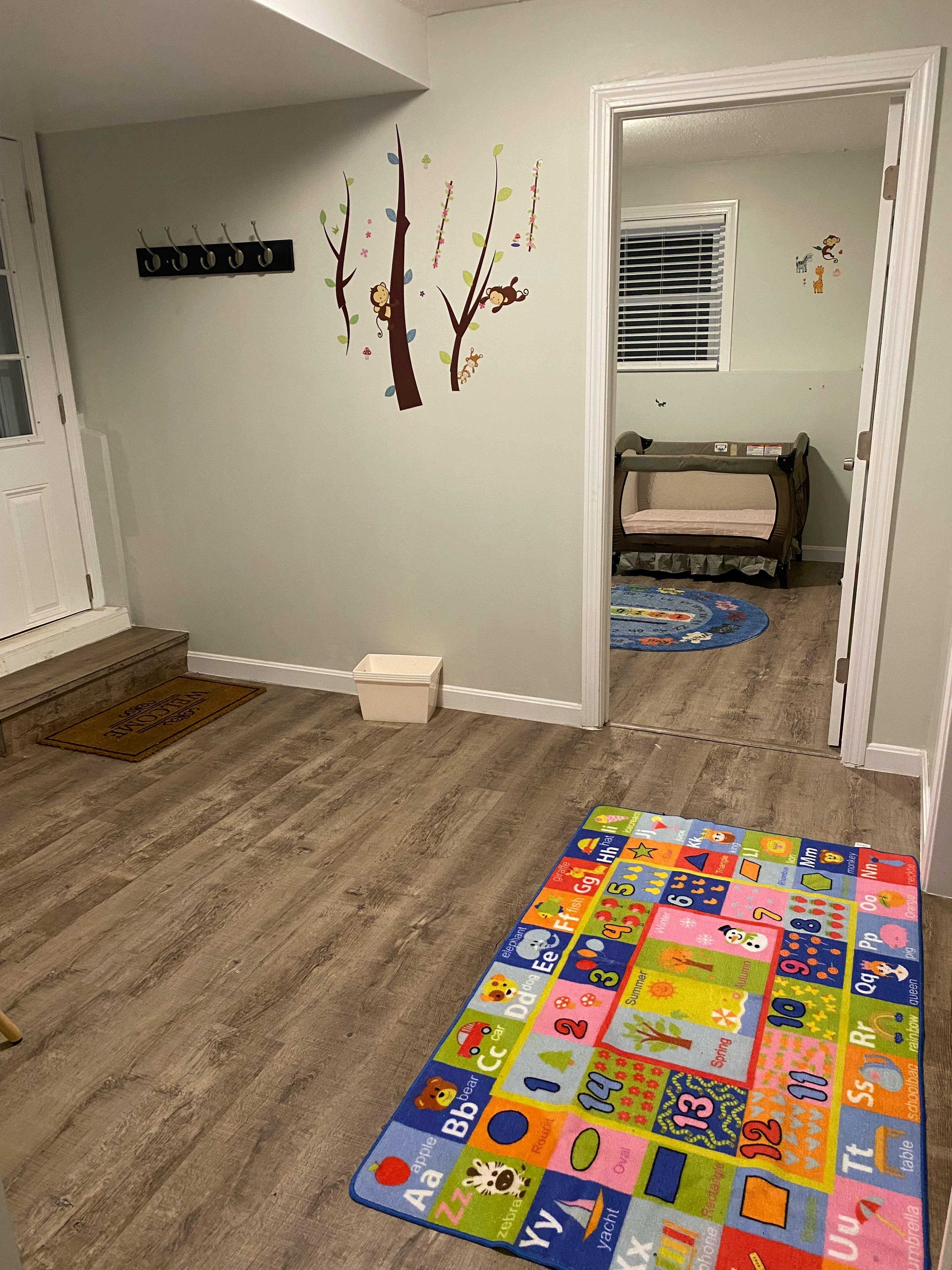 Room with a colorful alphabet rug and a changing table in the background