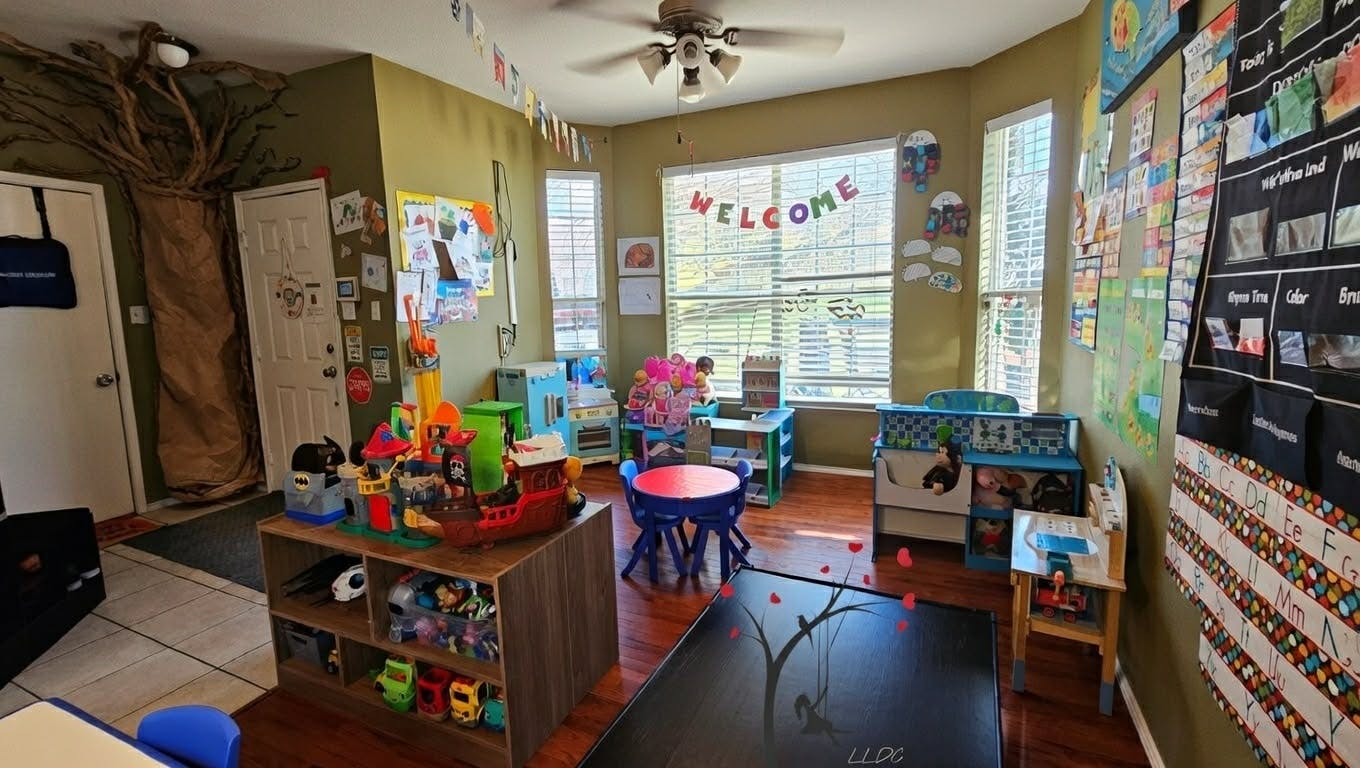 A colorful playroom with toys, a small table and chairs, and a welcome sign