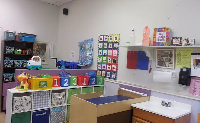 A classroom with shelves of toys, a changing table, and a sink