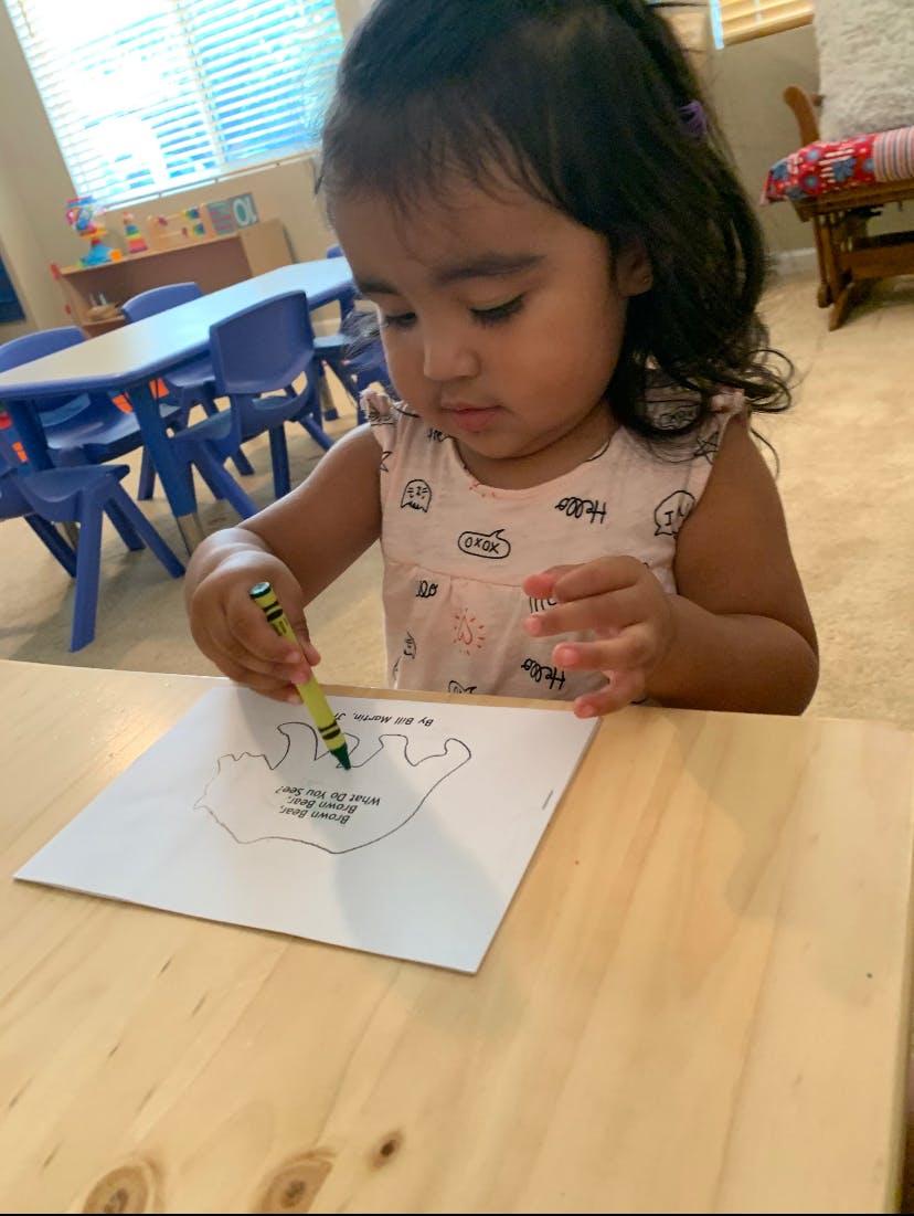 Child coloring a handprint outline with a yellow crayon