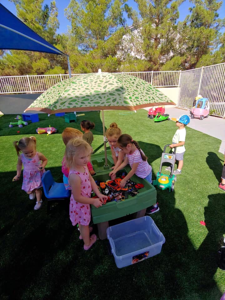 Children playing with toys in an outdoor area with artificial grass