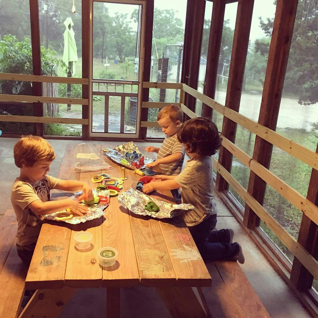 Three children playing with toys at a wooden table