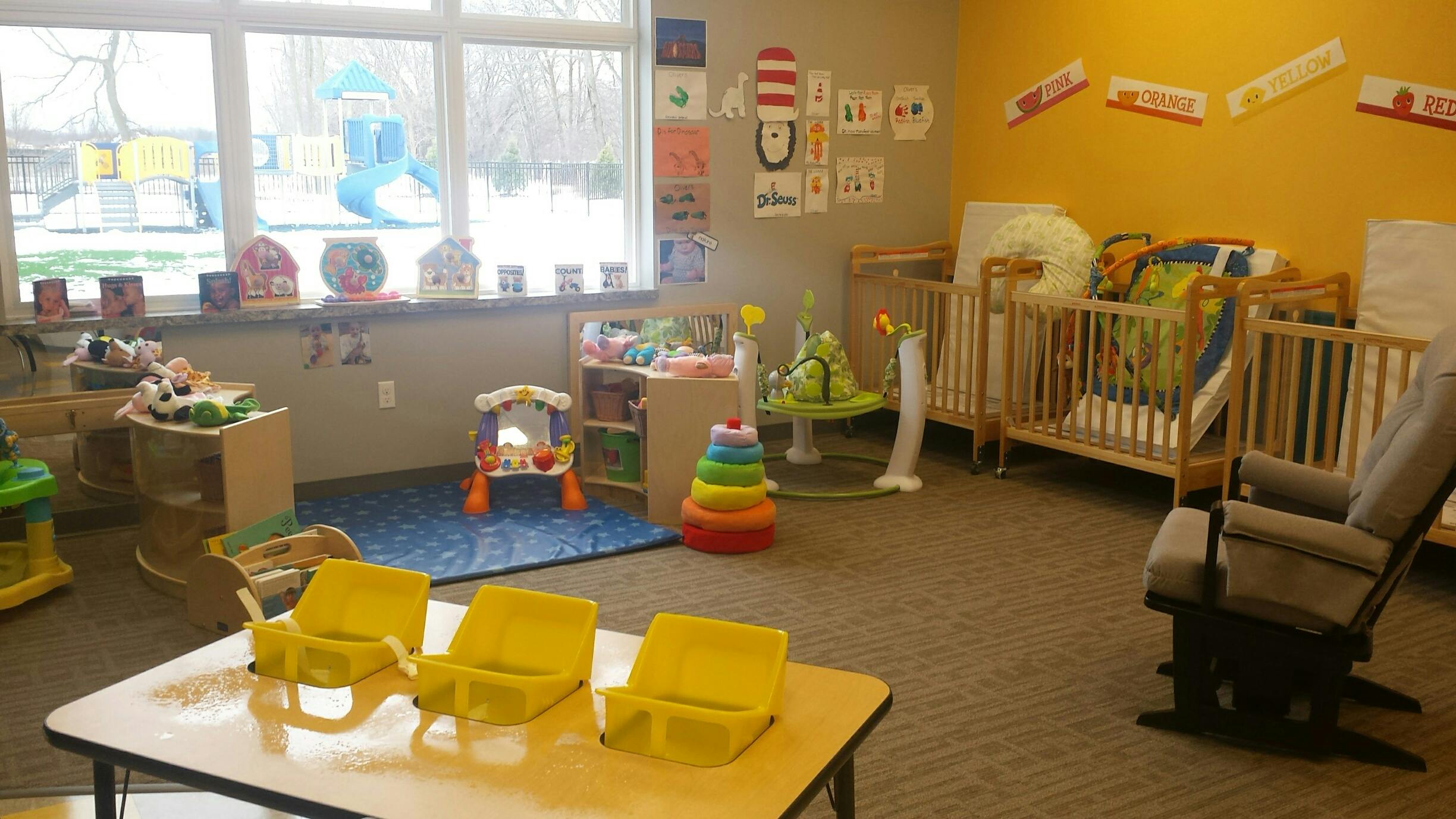 Daycare room with cribs, small chairs, and toys