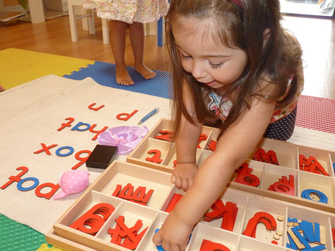 Child playing with letter tiles on a mat