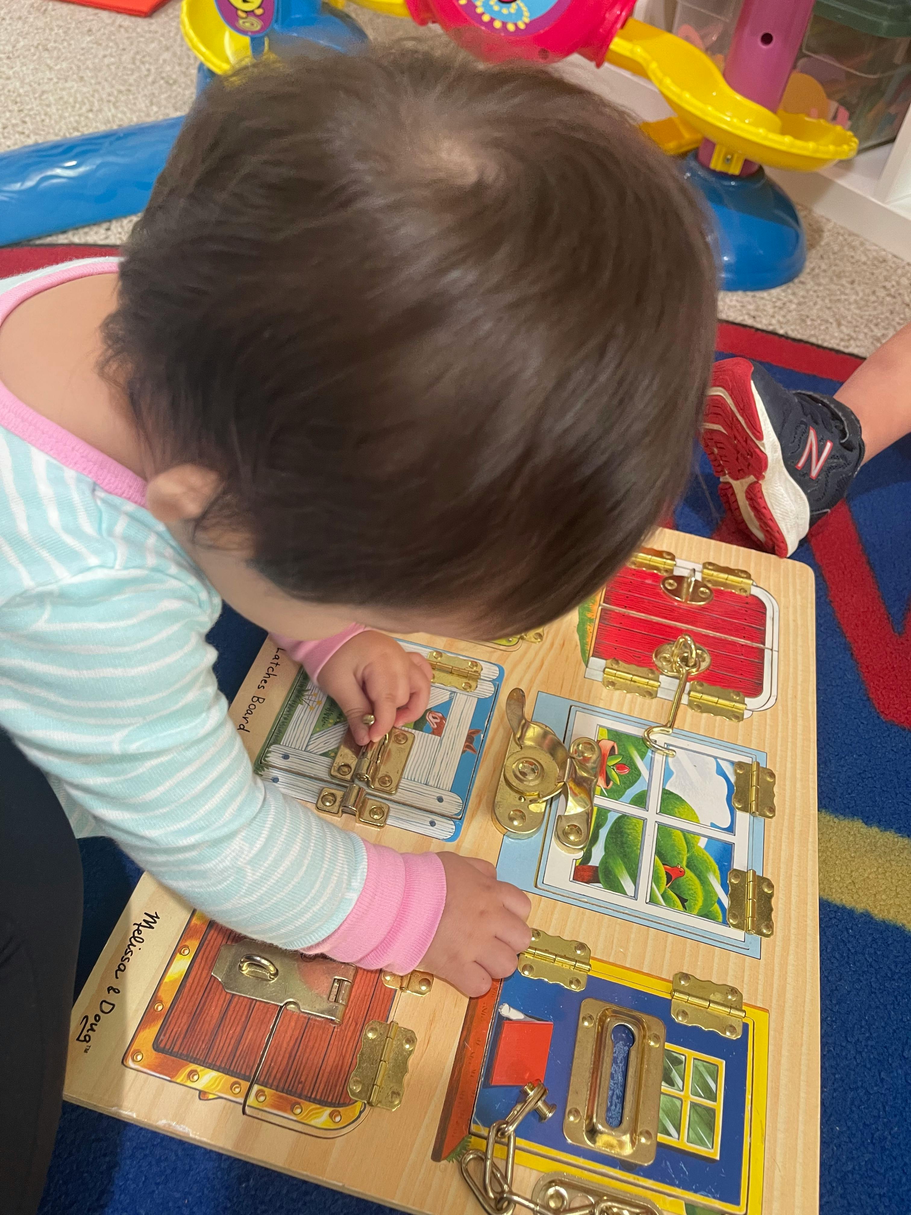 Child playing with a wooden latch board