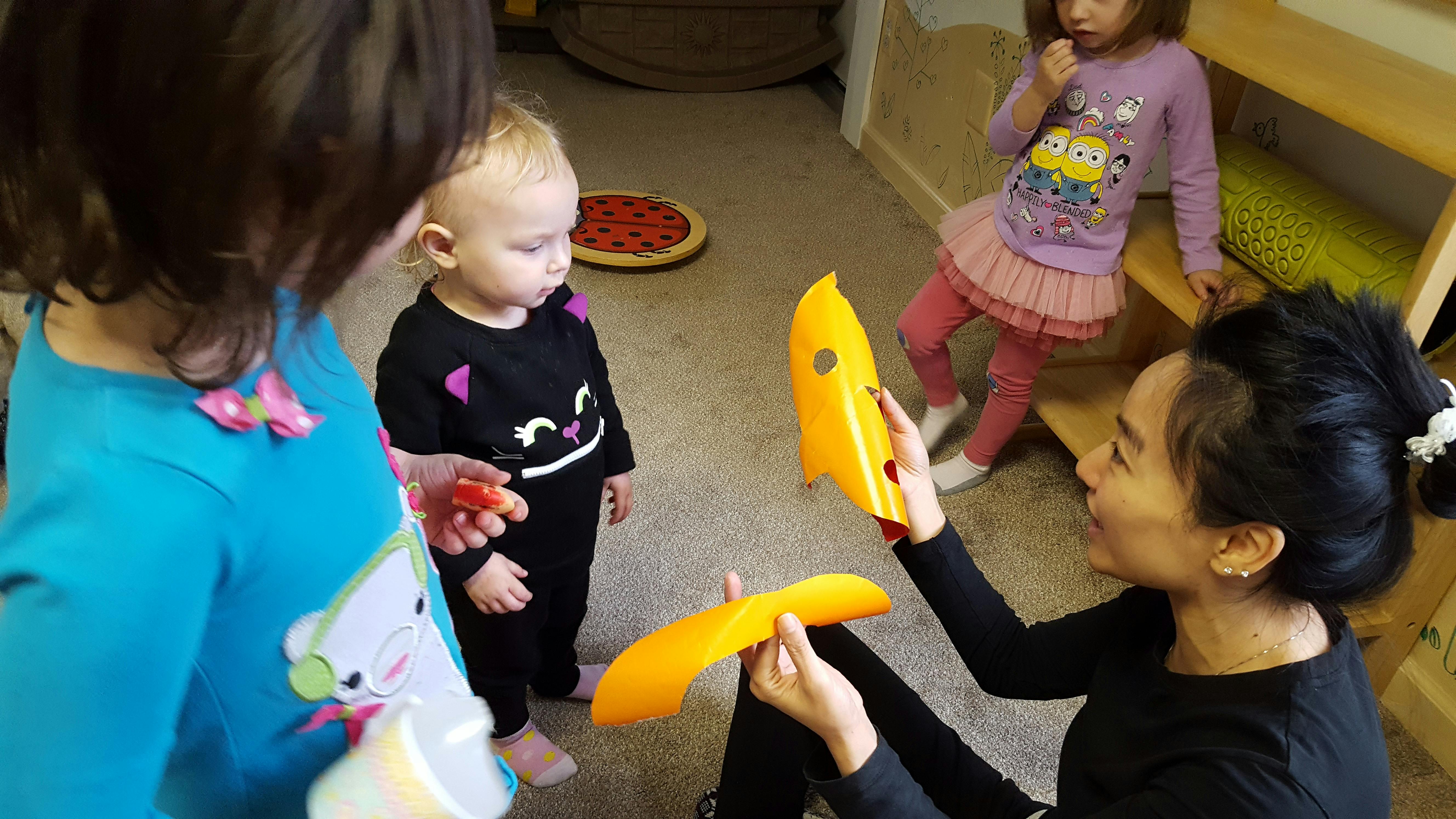 Adult and children playing with yellow toy pieces