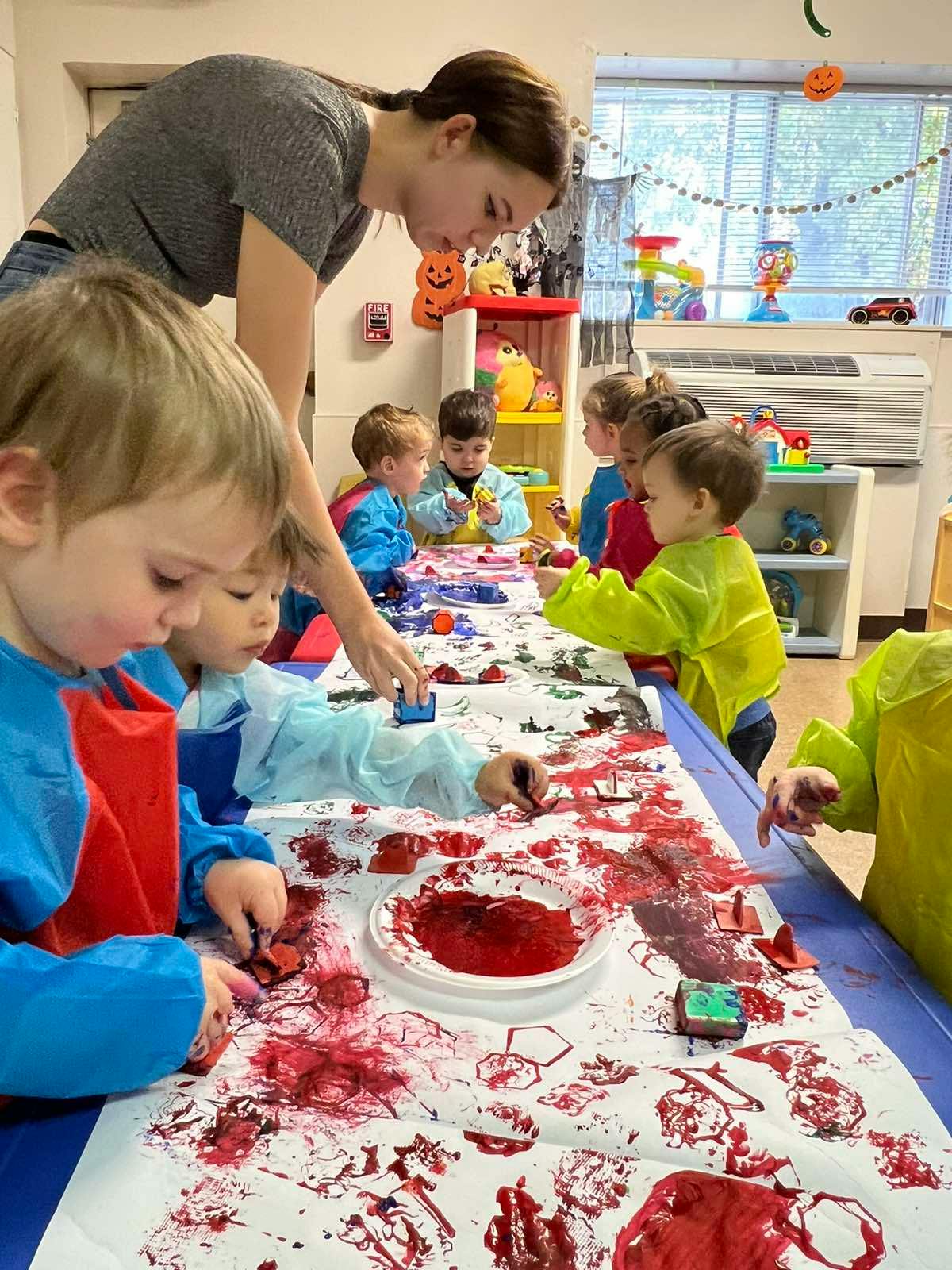 Adult and multiple children painting at a table