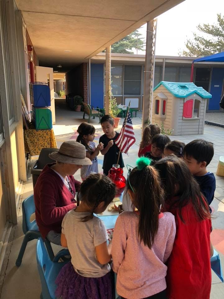 Adult and children gathered around a table outdoors